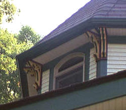 Pairs of triple layer brackets, painted with the home's accent colors, are mounted under the eaves of this Victorian tower